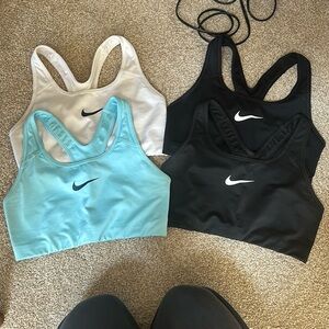 Nike sports bras. Size medium. 2 black, 1 white, 1 blue.